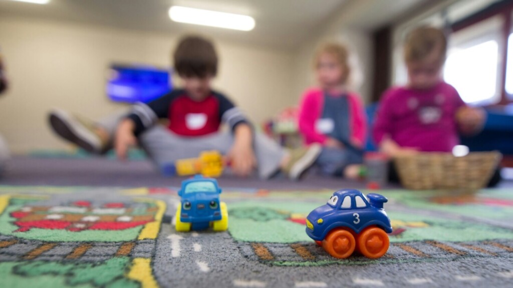 Kinderen spelen met speelgoedauto’s op kleed tijdens buitenschoolse opvang in groepsruimte