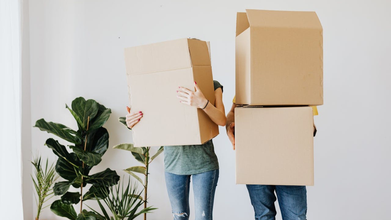 Twee personen tillen verhuisdozen in huis tijdens verhuizing met verhuisgarantie