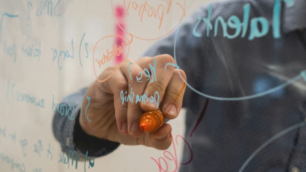 Hand schrijft met marker innovatief idee op glaswand tijdens brainstormsessie over innovatief denken