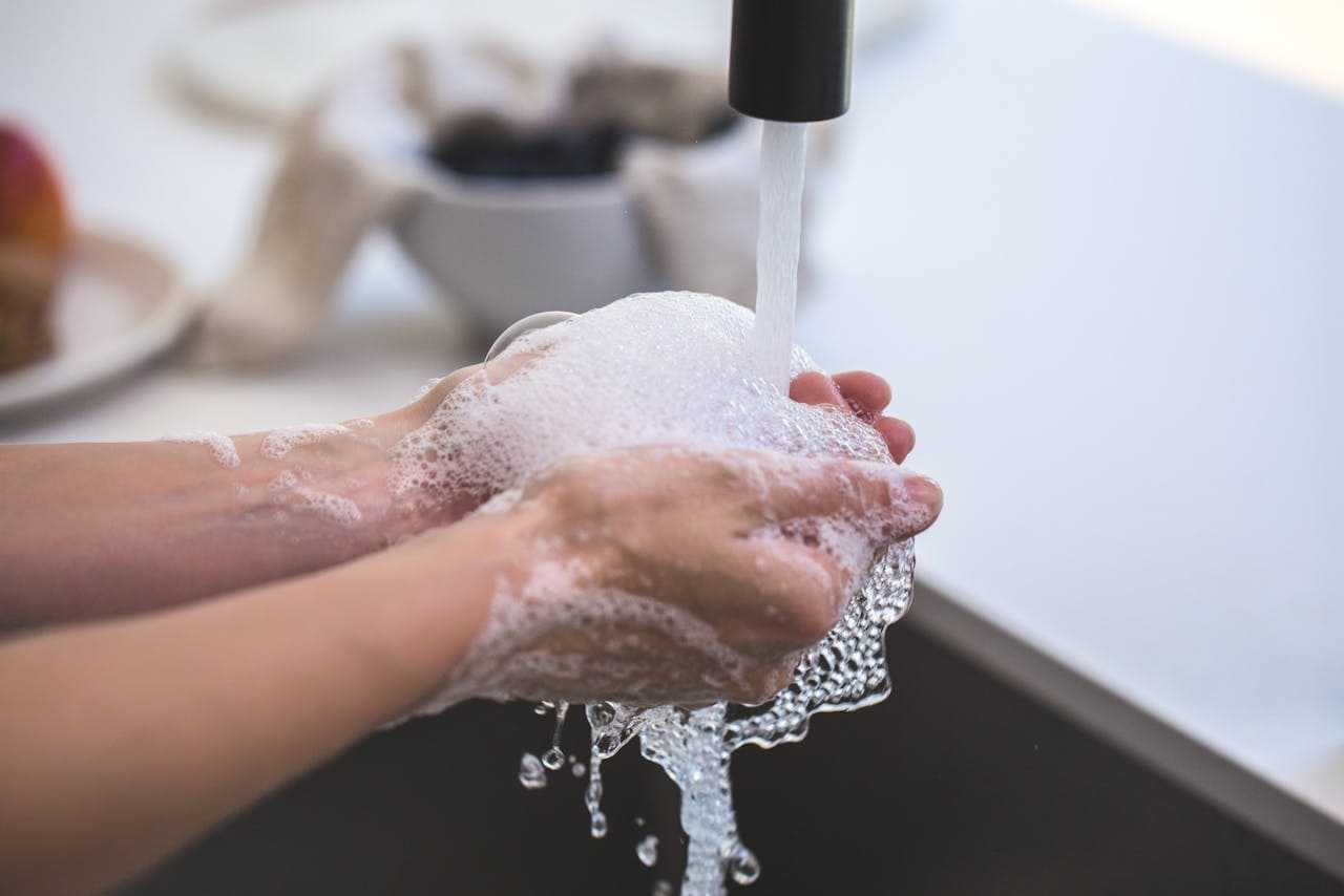 Handen wassen onder stromend water met veel schuim voor een schone omgeving en goede hygiëne