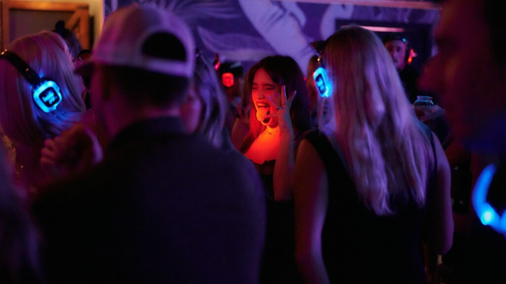 Dansende mensen met verlichte koptelefoons tijdens een silent disco in een donkere feestzaal