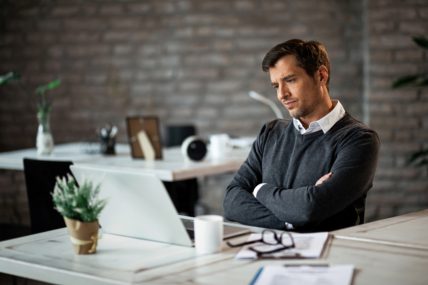 Ontevreden man die naar zijn computerscherm kijkt op kantoor.