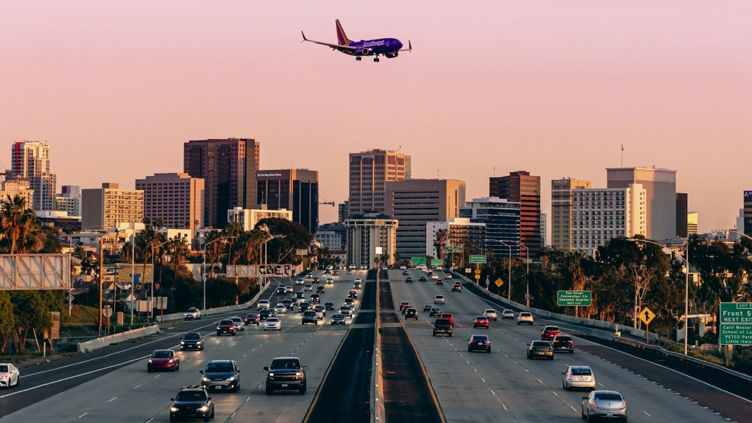 Vliegtuig met zichtbare e.t.a. nadert landingsbaan boven drukke snelweg bij zonsondergang