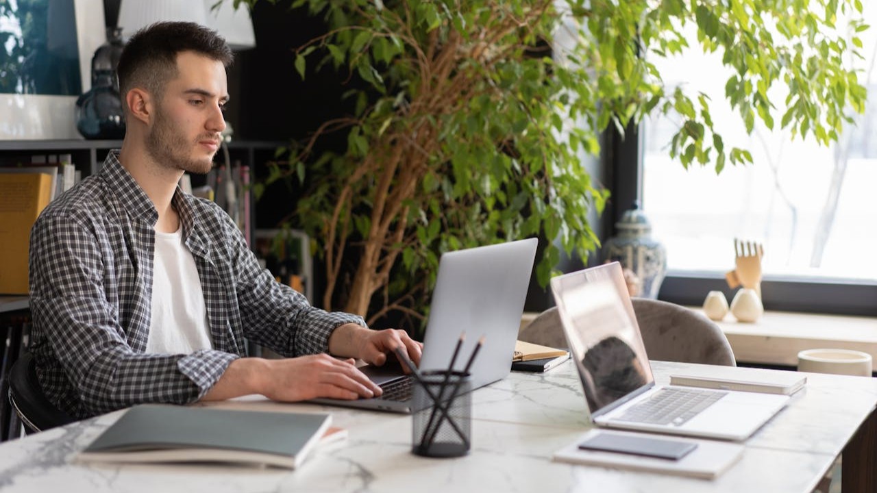 Man werkt aan laptop in moderne werkruimte met natuurlijk licht en focus op leads
